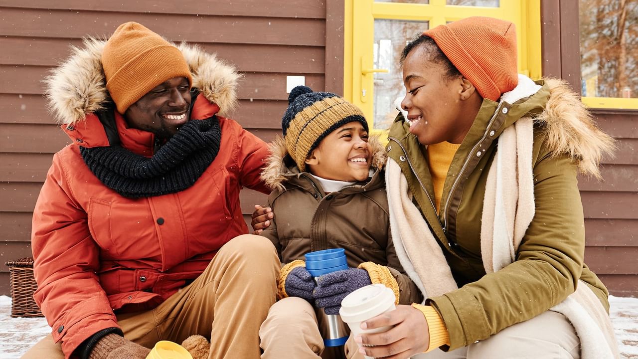 boy in winterwear sitting between parents wide